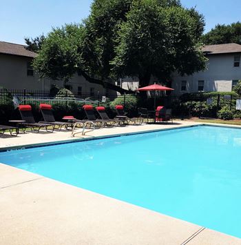 a swimming pool with lounge chairs and umbrellas next to a building at Avondale Station Apartments, Decatur, Georgia